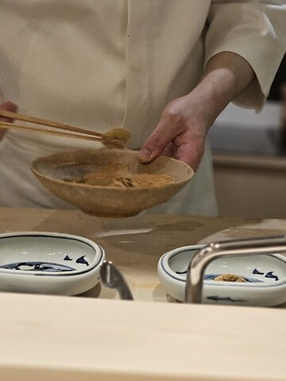 カウンター越しに器を差し出す主人の手元